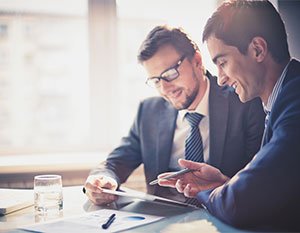 Two Men Sitting at Table Looking Over Papers with Business Insurance in OKC